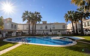 - une piscine dans une cour avec des palmiers dans l'établissement Adosado familiar frente a la piscina - Palm Beach ALBERT VILLAS Alcossebre, à Alcossebre