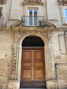 a large wooden door in a brick building with a balcony at Le tre scimmiette in Lanciano