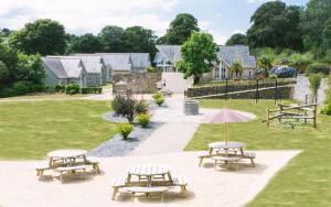 a group of picnic tables and an umbrella in a park at Trewhiddle Villa 30 in St Austell
