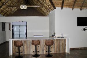 a kitchen with a bar with stools and a tv at Bluewave Farm Villa in Louis Trichardt