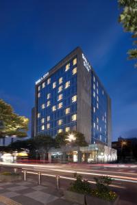 a tall building at night with traffic in front of it at Shilla Stay Jeju Airport in Jeju