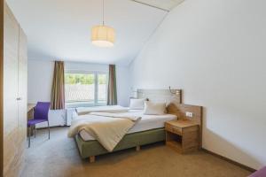 ein Schlafzimmer mit einem großen Bett und einem lila Stuhl in der Unterkunft Motel Engel - self checkin in Feldkirch