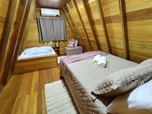 um quarto com uma cama e uma banheira em Chalé Magia das Hortênsias em Canela