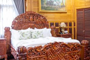 an ornate bed in a bedroom with a wooden wall at Phum Khmer Resort in Banlung