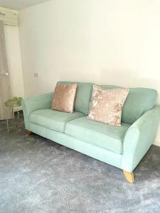 a green couch with two pillows on it in a room at 2.Superb Serviced Apartment - free on road parking in Birmingham