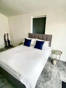 a bedroom with a large white bed with blue pillows at 2.Superb Serviced Apartment - free on road parking in Birmingham