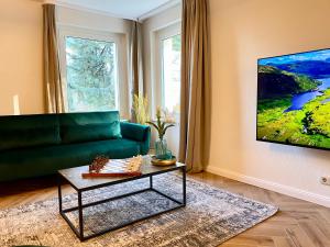 een woonkamer met een groene bank en een tafel bij Traumhaus Wernigerode mit Sauna und Kamin in Wernigerode
