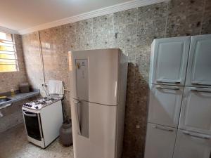 a kitchen with a white refrigerator and a stove at Casas 5 min a pé da praia in Natal