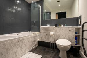 a bathroom with a toilet and a tub and a sink at JPG Theatre Suite - High Floor MCR Luxe Apartment w Balcony Canal Views in Manchester