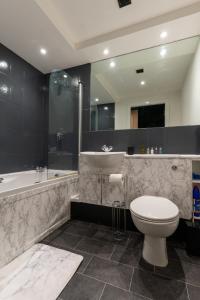 a bathroom with a toilet and a tub and a sink at JPG Theatre Suite - High Floor MCR Luxe Apartment w Balcony Canal Views in Manchester