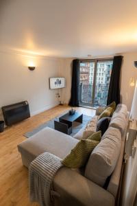 a living room with a couch and a large window at JPG Theatre Suite - High Floor MCR Luxe Apartment w Balcony Canal Views in Manchester