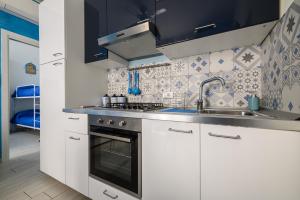 uma cozinha com armários brancos, um lavatório e um fogão em Appartamento Luci d'Artista em Vietri