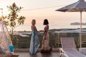 Falasarna Luxury Villas في فالاسارنا: سيدتان واقفتان على شرفة تطل على المحيط