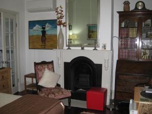 a living room with a fireplace and a chair at Three Chimneys Bed and Breakfast Boutique Guest House in Albany +8 photos