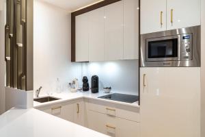 a white kitchen with a sink and a microwave at Fauriel Paul - Appartement moderne et spacieux in Saint-Étienne