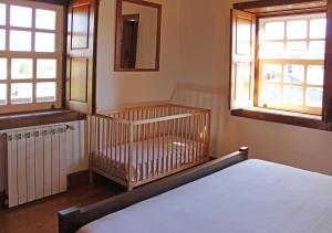 a bedroom with a crib and two windows at Casa dos três rapazes in Monte Córdova +69 photos