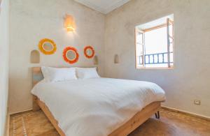 a bedroom with a large white bed and a window at Stella 2 - appartement spacieux avec cheminée medina Essaouira in Essaouira