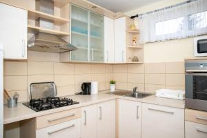a kitchen with white cabinets and a stove top oven at Apartmani i Sobe Kočiš in Bjelovar