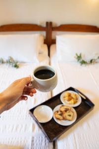 una persona sosteniendo una taza de café y una bandeja de comida en Hotel Cleopatra en Chorefto