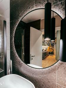 Baño con espejo redondo sobre un lavabo en B&B SALUS CIVICO 23, en Reggio Emilia