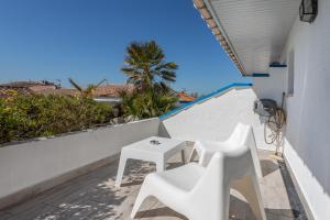 d'un balcon avec des chaises blanches, une table et un palmier. dans l'établissement Hotel Les Palmiers En Camargue, à Saintes-Maries-de-la-Mer