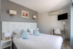 a bedroom with a large white bed with blue pillows at Hotel Les Palmiers En Camargue in Saintes-Maries-de-la-Mer