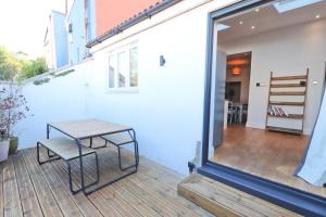 un patio con una mesa y un banco en una terraza en Terracotta House en Bristol