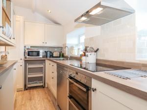 Una cocina con gabinetes blancos y encimera. en Garden Cottage, en Chathill