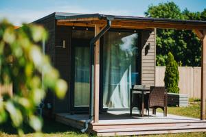 Cabaña pequeña con porche con mesa y sillas en Liepa SaulesKempings, en Mērsrags