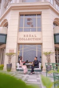 two people sitting at a table in front of a building at Regal Collection House in Dương Cảnh
