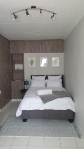 Refreshing Space in Eden Glen, Johannesburg, SA في ايدنفيل: غرفة نوم بسرير كبير مع شراشف بيضاء