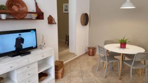 ein Wohnzimmer mit einem TV und einem Tisch mit Stühlen in der Unterkunft La Casa più Bella in Custonaci