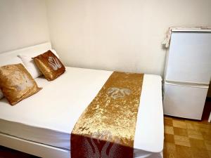 1 dormitorio con 1 cama con almohadas de oro y nevera en 豊島園ー　kyoka house, en Tokio