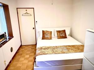 1 dormitorio pequeño con 1 cama blanca y 2 almohadas en 豊島園ー　kyoka house, en Tokio