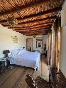 um quarto com uma cama branca e um tecto de madeira em Riad Al Massarah em Marraquexe