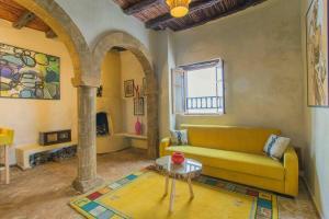 a living room with a yellow couch and a table at Stella 3 - superbe appartement avec cheminée en médina in Essaouira