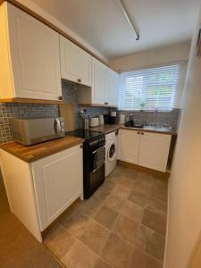 a kitchen with white cabinets and a stove top oven at Eremue Court Hideaway Yarmouth IOW in Yarmouth