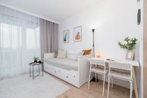 a white bedroom with a bed and a desk at Saska Blu Studio Apartments Podgórze by Renters in Krakow