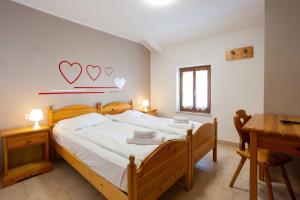 1 dormitorio con 1 cama con 2 corazones en la pared en Santa Maria ad Nives, en Canazei