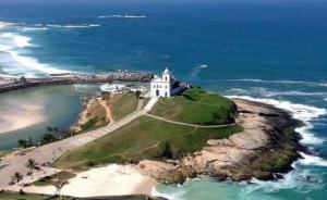 un faro su un'isola nell'oceano di POUSADA ARKAN BEACH a Saquarema