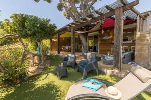 a backyard with a table and chairs and a house at La Félyvonne, villa familiale confortable avec sa grande terrasse ombragée et sa vue dégagée vers la mer in Hyères