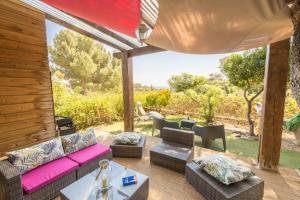a patio with a couch and chairs and a table at La Félyvonne, villa familiale confortable avec sa grande terrasse ombragée et sa vue dégagée vers la mer in Hyères