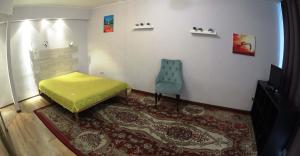 Habitación con cama amarilla y silla azul. en Apartments near Railway Station, en Novosibirsk