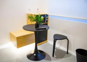 a black table with a plant on it next to a stool at KALIDAS HOSTEL SUITES in Caldas de Reis