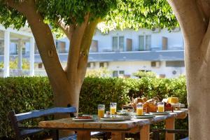 une table en bois avec de la nourriture sous un arbre dans l'établissement Vasia Ormos Hotel (Adults Only), à Agios Nikolaos