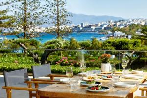 a wooden table with plates of food and wine glasses at Vasia Ormos Hotel (Adults Only) in Agios Nikolaos