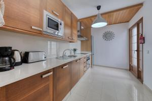 a kitchen with wooden cabinets and a sink and a microwave at Villa Flavia-private pool, jacuzzi, sea views in Playa Blanca