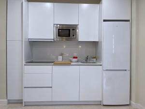 a white kitchen with white cabinets and a microwave at Apartamento Arquillo de la Plata in Seville