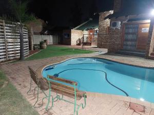 una piscina por la noche con un banco al lado en Twins Guest House Astoni en Vanderbijlpark