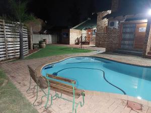 a swimming pool at night with a bench next to it at Twins Guest House Astoni in Vanderbijlpark